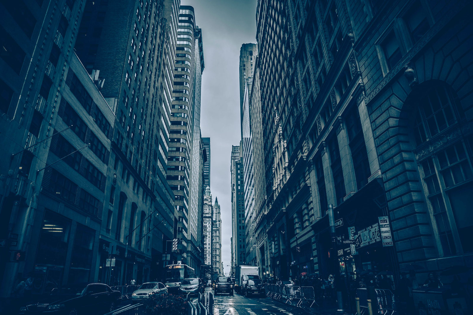 Rainy urban street flanked by tall skyscrapers