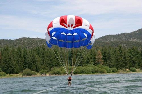 Person parasailing over lake with colorful parachute